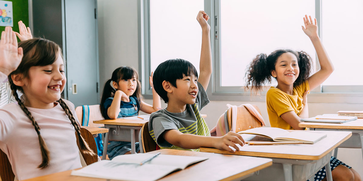 students raising their hands in classroom